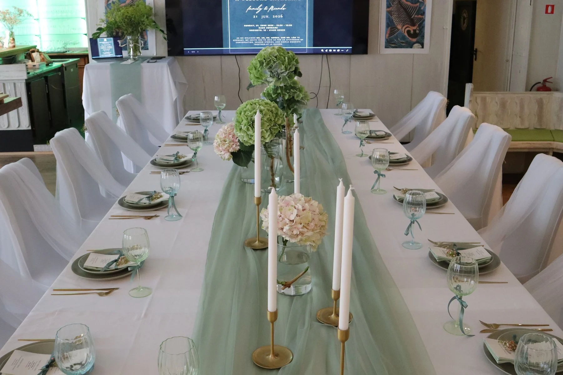 Long table with sage-green runner, candles and hydrangeas set for a family gathering at Haus Jordans, Neuss
