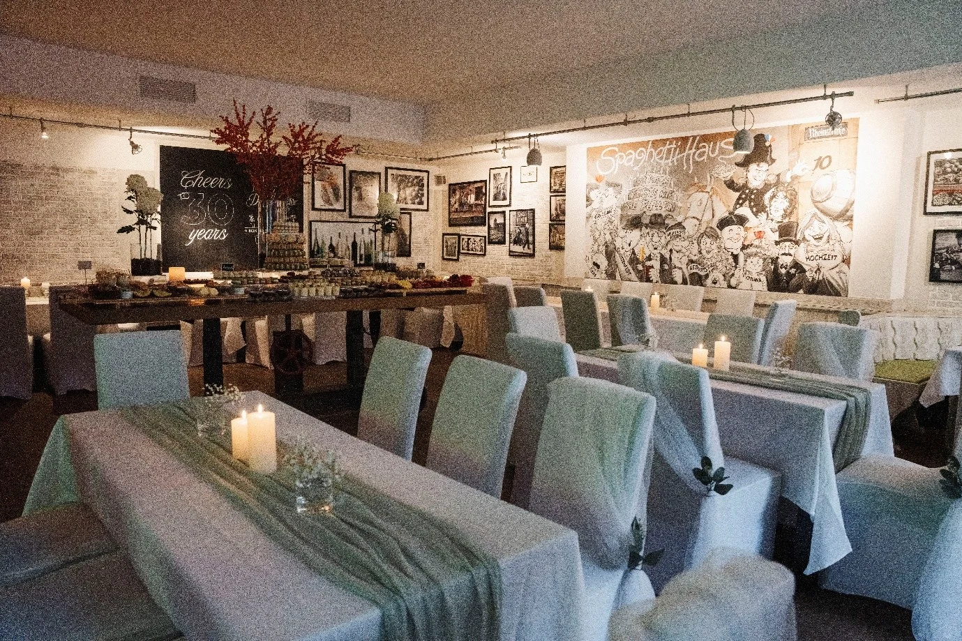 Dining room at Haus Jordans set for a private event, with white chair covers, sage-green runners and candles, Neuss