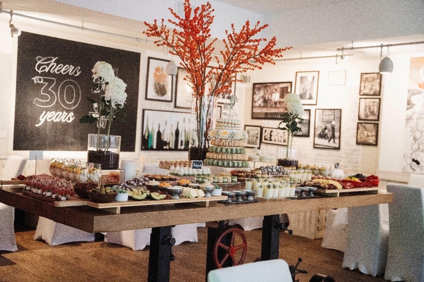 Buffet with macaron tower in front of a "Cheers to 30 years" chalkboard at an anniversary celebration at Haus Jordans, Neuss